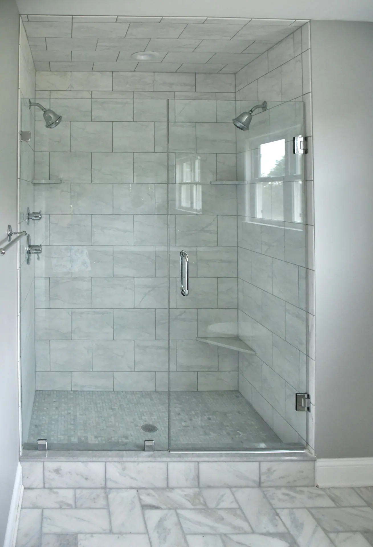 Frameless glass shower enclosure with clear glass door and marble tile walls